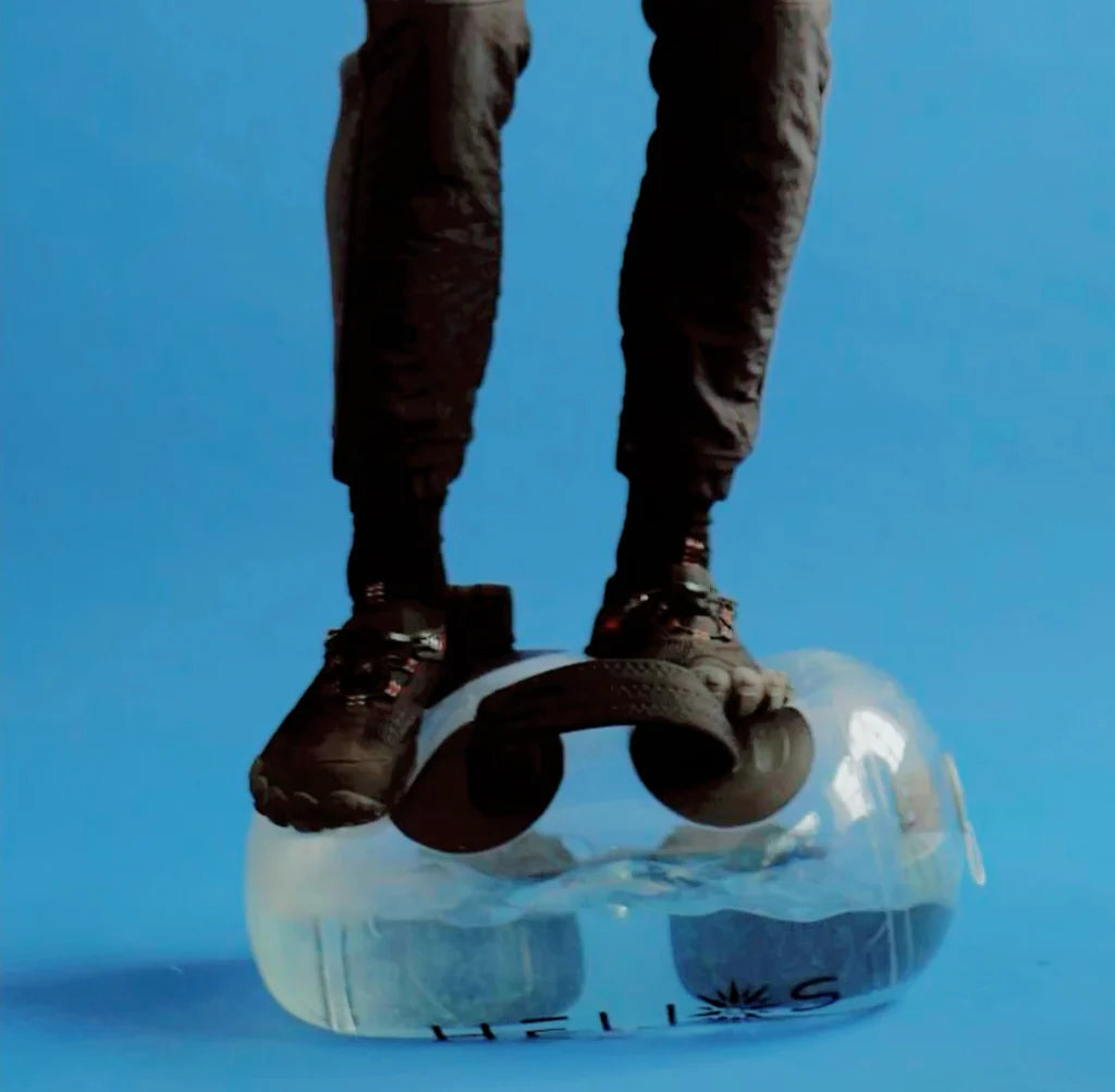Person standing on the water-filled HELIOS bag to demonstrate its durability, blue background