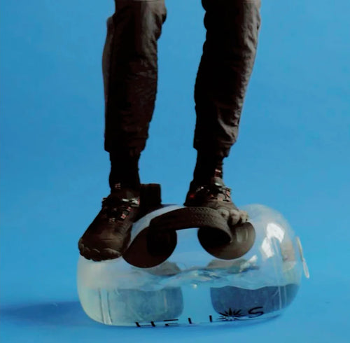 Person standing on the water-filled HELIOS bag to demonstrate its durability, blue background