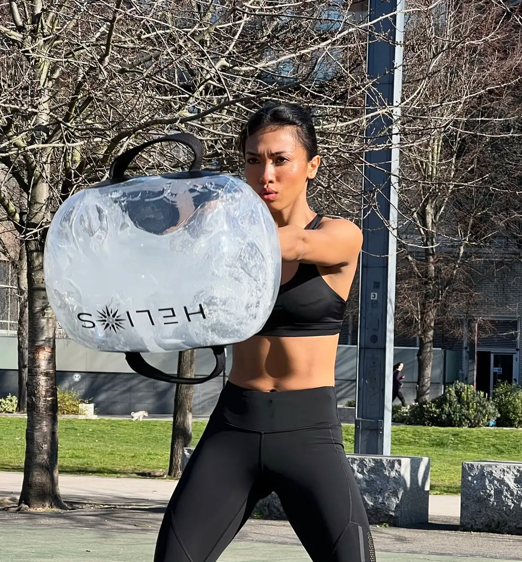 Athlete training outdoors in a park, swinging the water-filled HELIOS weight bag