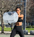 Athlete training outdoors in a park, swinging the water-filled HELIOS weight bag