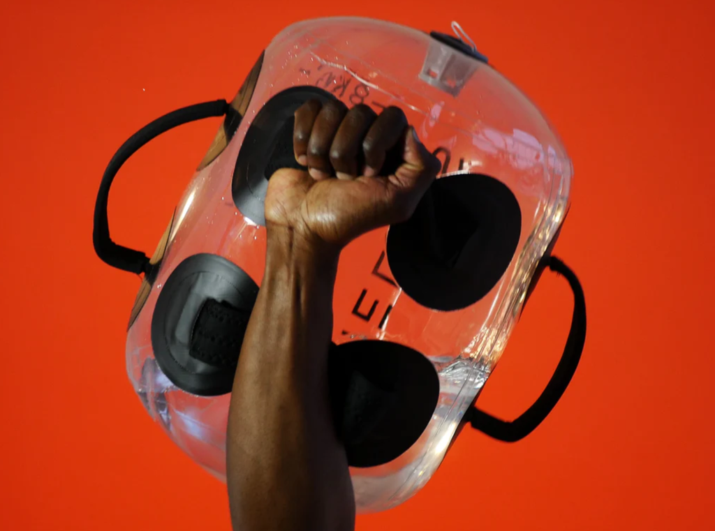 Athlete's fist gripping the HELIOS water weight bag against a bold red background
